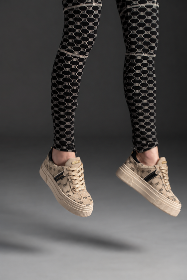 Beige platform sneakers with BAMBURI monogram, exposed laces and gold tongue nameplates, worn on feet