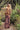Woman carrying a tan fringed bag with a BAMBURI heart keychain among green succulents
