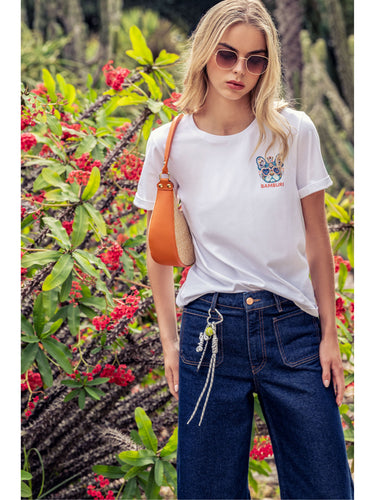 胸元に小さなマルチカラーのブルドッグ グラフィックを配したホワイトBAMBURI Tシャツを着た女性